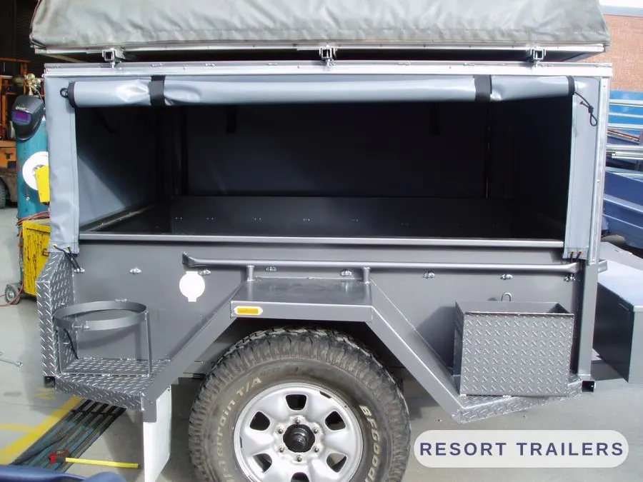 Off-road camper with the canopy open, showing the checker-plate floor — built by Resort Trailers
